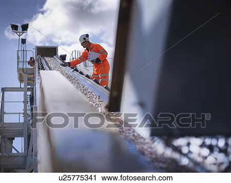 Worker examining stones on conveyor belt View Large Photo Image Stock Image - Worker examining stones on conveyor belt. Fotosearch