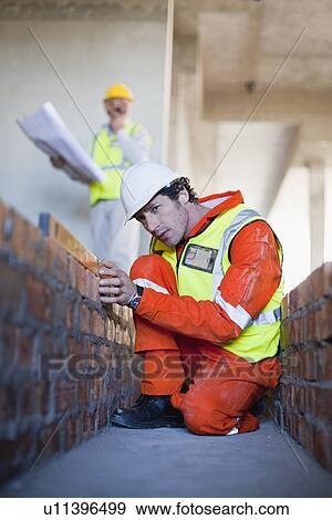 Worker laying brick at construction site View Large Photo Image Stock Photo - Worker laying brick at construction site. Fotosearch