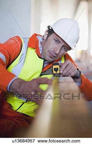 Worker measuring brick on site View Large Photo Image Stock Photo - Worker measuring brick on site. Fotosearch