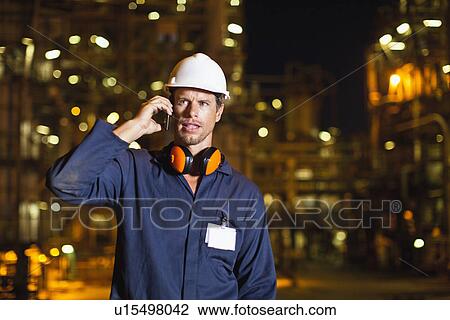 Worker on cell phone at oil refinery View Large Photo Image Stock Image - Worker on cell phone at oil refinery. Fotosearch