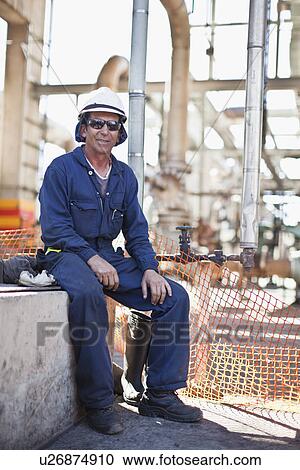 Stock Image - Worker sitting at oil refinery. Fotosearch