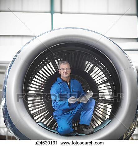 Stock Image - Worker sitting in airplane engine. Fotosearch