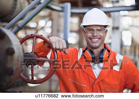 Stock Image - Worker smiling at oil refinery. Fotosearch