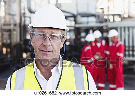 Stock Image - Worker standing at chemical plant. Fotosearch