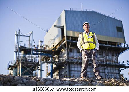 Stock Photo - Worker standing at chemical plant. Fotosearch