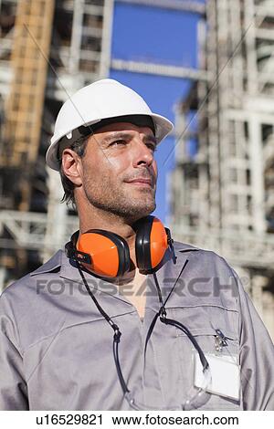 Stock Image - Worker standing at oil refinery. Fotosearch