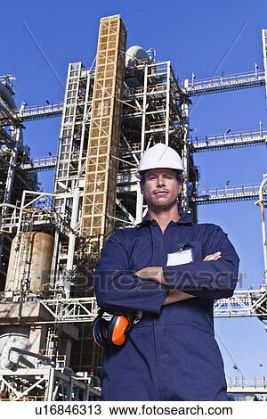 Stock Image - Worker standing at oil refinery. Fotosearch
