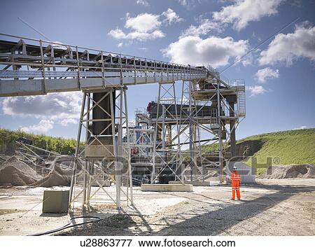 Worker standing by conveyor in quarry View Large Photo Image Stock Photo - Worker standing by conveyor in quarry. Fotosearch