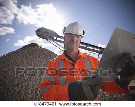 Worker standing by pile of stones View Large Photo Image Stock Image - Worker standing by pile of stones. Fotosearch