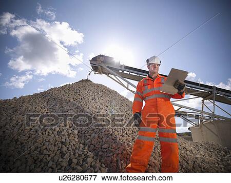 Worker standing by pile of stones View Large Photo Image Stock Photo - Worker standing by pile of stones. Fotosearch