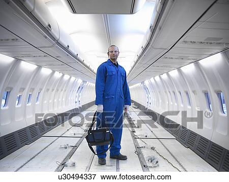 Stock Photo - Worker standing in empty airplane. Fotosearch