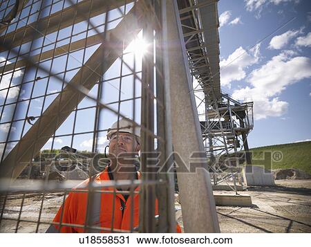 Worker standing under conveyor in quarry View Large Photo Image Stock Image - Worker standing under conveyor in quarry. Fotosearch