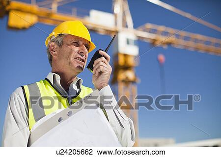 Stock Image - Worker using walkie talkie on site. Fotosearch