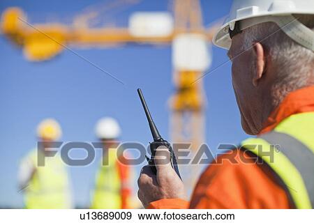 Worker using walkie talkie on site View Large Photo Image Stock Photo - Worker using walkie talkie on site. Fotosearch