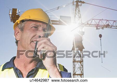 Stock Photo - Worker using walkie talkie on site. Fotosearch