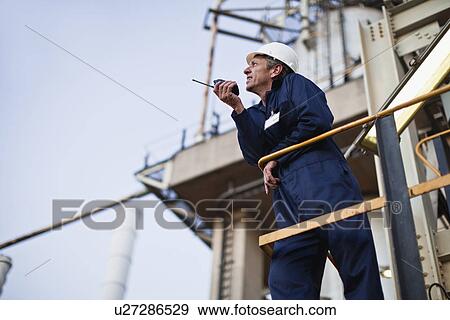 Worker using walkie talkie on site View Large Photo Image Stock Photo - Worker using walkie talkie on site. Fotosearch