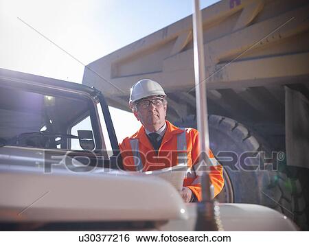 Stock Photograph - Worker with blueprints in coal mine. Fotosearch