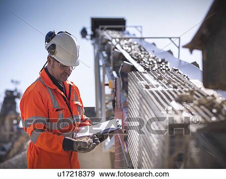 Stock Photo - Worker with clipboard by conveyor belt. Fotosearch
