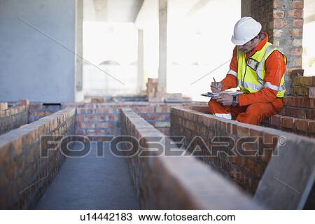 Worker writing on clipboard on site View Large Photo Image Stock Image - Worker writing on clipboard on site. Fotosearch