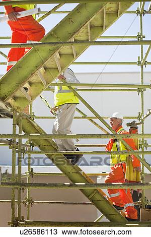 Stock Image - Workers climbing steps on site. Fotosearch