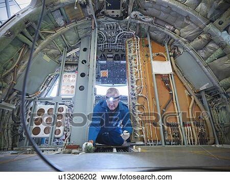 Stock Image - Workers examining airplane machinery. Fotosearch