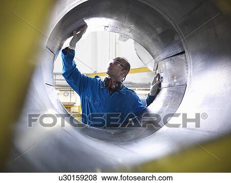 Stock Photo - Workers examining airplane machinery. Fotosearch