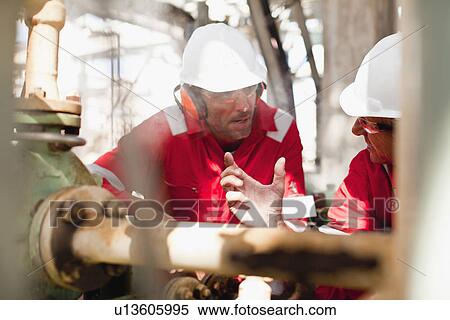 Stock Photography - Workers examining equipment on site. Fotosearch