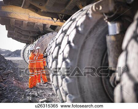 Stock Photography - Workers examining trucks in coal mine. Fotosearch
