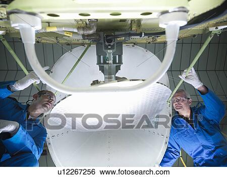 Stock Photograph - Workers fitting nose to airplane. Fotosearch