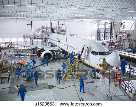 Stock Image - Workers in airplane hangar. Fotosearch