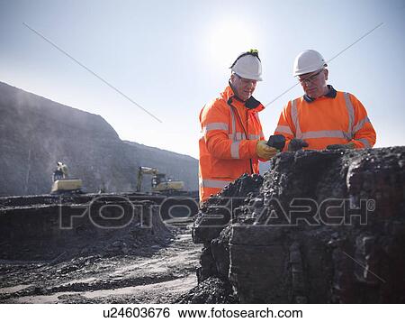 Stock Photograph - Workers inspecting coal at mine. Fotosearch