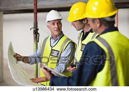 Workers reading blueprints on site View Large Photo Image Picture - Workers reading blueprints on site. Fotosearch