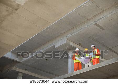 Workers reading blueprints on site View Large Photo Image Picture - Workers reading blueprints on site. Fotosearch