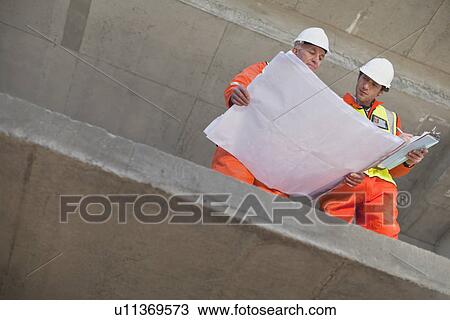 Workers reading blueprints on site View Large Photo Image Stock Image - Workers reading blueprints on site. Fotosearch
