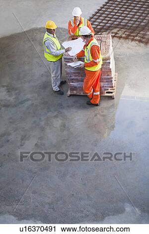 Workers reading blueprints on site View Large Photo Image Stock Image - Workers reading blueprints on site. Fotosearch