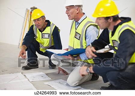 Workers reading blueprints on site View Large Photo Image Stock Image - Workers reading blueprints on site. Fotosearch