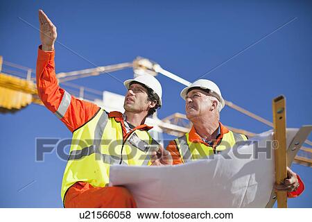 Workers reading blueprints on site View Large Photo Image Stock Photo - Workers reading blueprints on site. Fotosearch