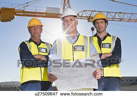 Stock Photo - Workers reading blueprints on site. Fotosearch