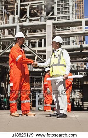 Stock Photo - Workers shaking hands at oil refinery. Fotosearch