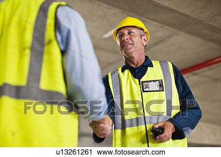 Workers shaking hands on site View Large Photo Image Stock Image - Workers shaking hands on site. Fotosearch