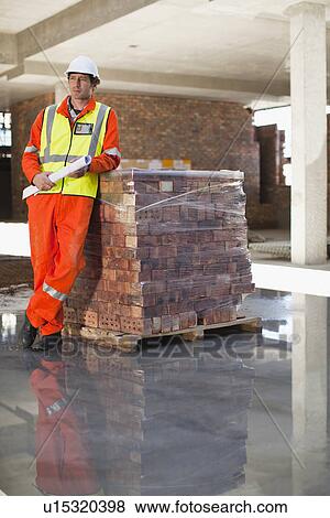 Workers standing at construction site View Large Photo Image Stock Photo - Workers standing at construction site. Fotosearch