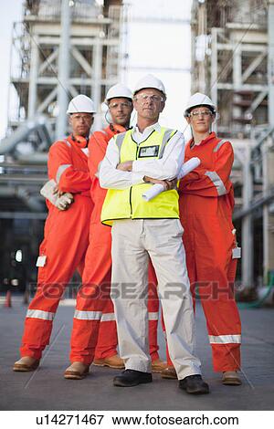Stock Photo - Workers standing at oil refinery. Fotosearch