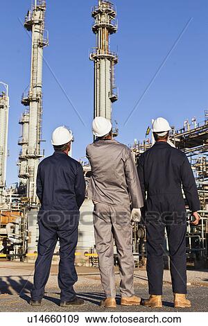 Workers standing at oil refinery View Large Photo Image Stock Photo - Workers standing at oil refinery. Fotosearch
