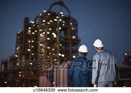 Stock Photo - Workers standing at oil refinery. Fotosearch