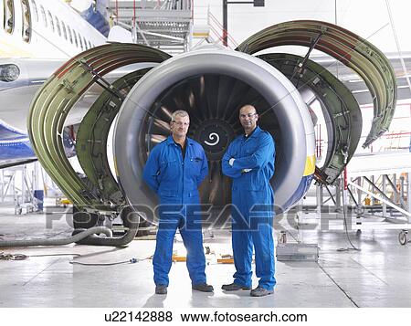 Workers standing by airplane engine View Large Photo Image Stock Photo - Workers standing by airplane engine. Fotosearch