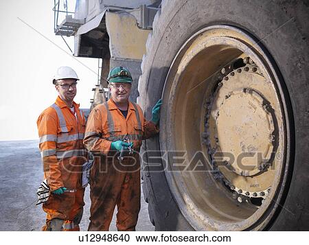 Stock Image - Workers standing by truck at coal mine. Fotosearch