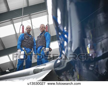 Workers standing on airplane wing View Large Photo Image Stock Photo - Workers standing on airplane wing. Fotosearch