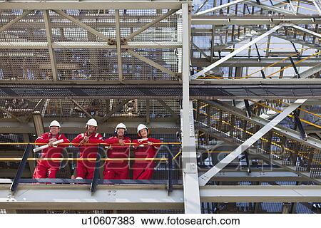 Stock Image - Workers standing on ledge together. Fotosearch