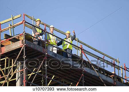 Stock Image - Workers standing on scaffolding on site. Fotosearch