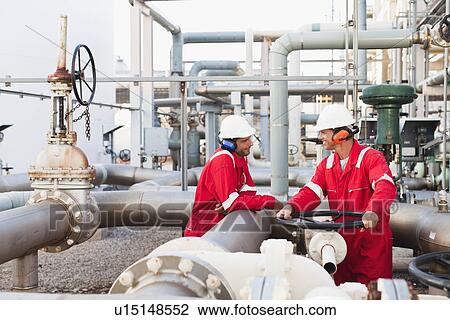 Stock Image - Workers talking at chemical plant. Fotosearch